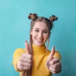 Young student in yellow top with both thumbs up